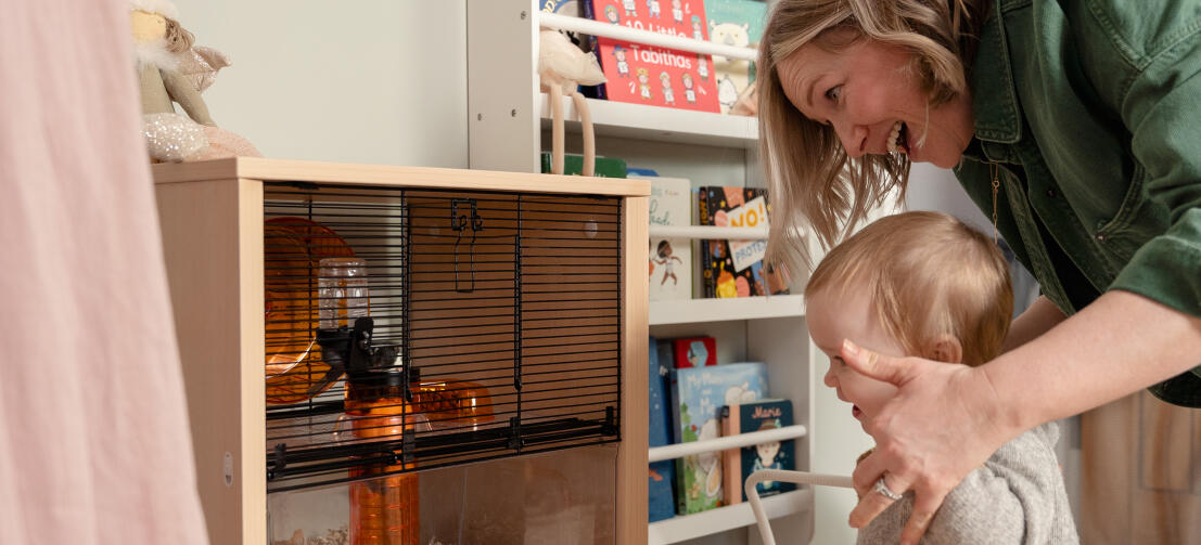 Une mère et son bébé appréciant de voir un hamster dans la cage de Qute.