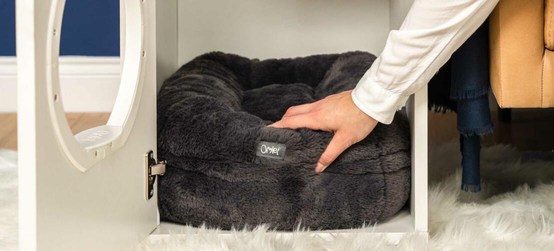 Personne mettant le lit pour chat noir Maya donut à l'intérieur de la maison pour chat d'intérieur Maya