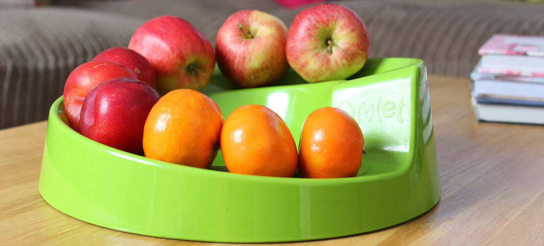 Un bol à fruits vert rollabowl avec beaucoup de fruits dessus.