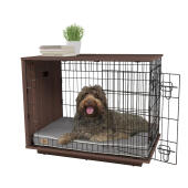 Un chien assis à l'intérieur d'une caisse pour chien en noyer Omlet Fido Studio .