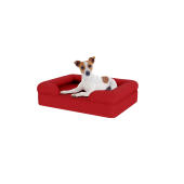 Chien assis sur un petit lit pour chien en mousse à mémoire de forme rouge merlot