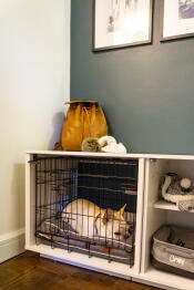 Un chien blanc endormi à l'intérieur d'un Fido Nook avec une armoire et une caisse