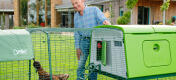 Homme avec un grand poulailler Eglu dans un jardin