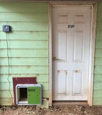 Un ouvre-porte automatique pour les poules fixé à l'extérieur de la maison