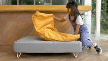 Petite fille retirant un pouf jaune Topology topper