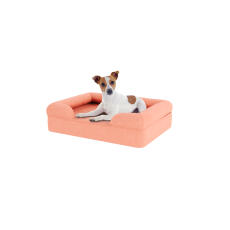 Chien assis sur un petit lit pour chien en mousse à mémoire de forme rose pêche