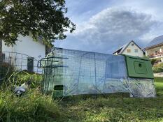 Un poulailler et un parcours avec des poignées à l'extrémité du parcours, couverts par des bâches transparentes