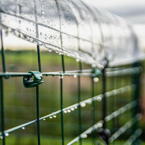 Détail latéral de la couverture transparente de protection contre les intempéries fixée à la piste d'athlétisme