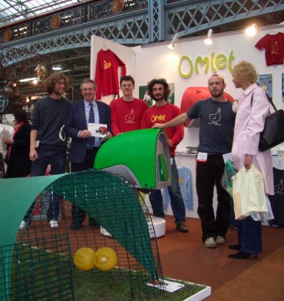 Un groupe de personnes posant sur un stand avec le poulailler Eglu Cube 