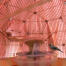 Un oiseau modèle perché sur une manGeoire à l'intérieur d'une cage à oiseaux rose avec un miroir