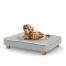 Un chiot se reposant sur le petit lit pour chiot Topology avec des pieds ronds en bois