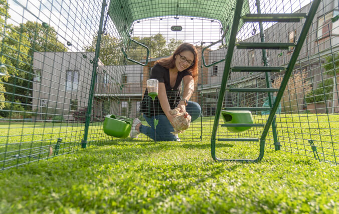 femme qui se penche sur l’enclos du poulailler eglu cube
