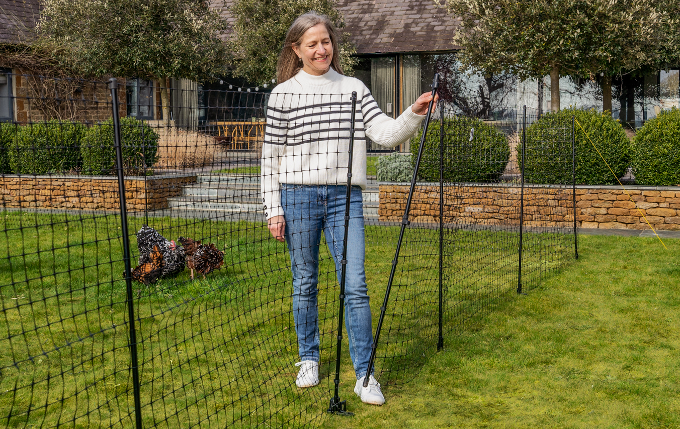 Filets à poules dans un jardin avec une femme devant l’entrée intégrée