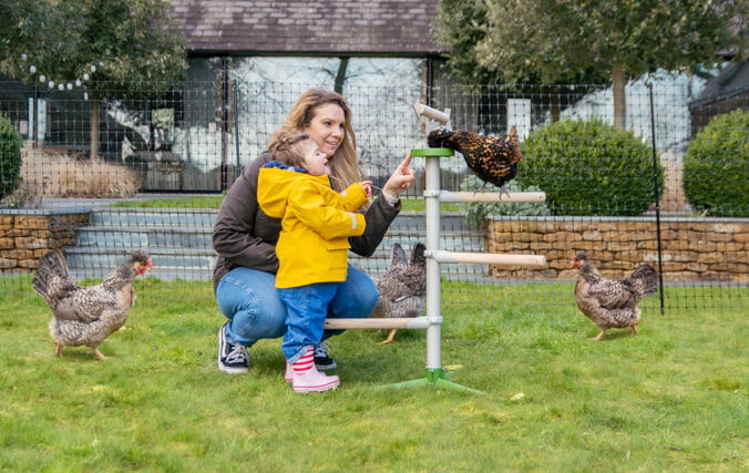 maman et sa fille qui jouent avec leurs poules dans le jardin