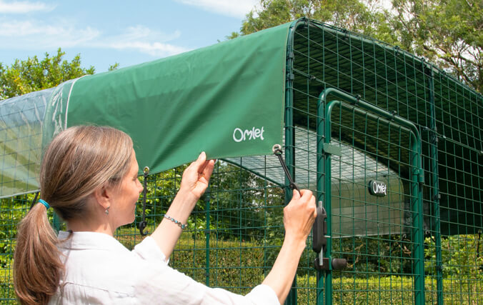 Femme qui attache une bâche pour enclos sur un catio Omlet / enclos pour chat jardin