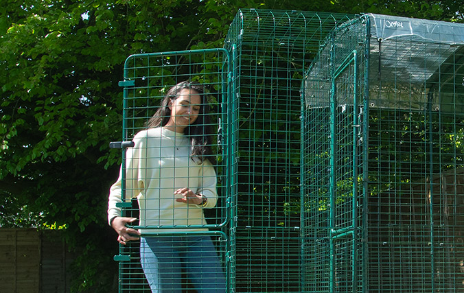 Femme entrant dans un Grand Enclos pour chat avec un porche omlet / enclos pour chats jardin